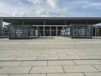 a building made out of glass and a courtyard outside with a brick walkway and a stone tile patio