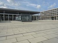 a building made out of glass and a courtyard outside with a brick walkway and a stone tile patio