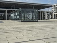 a building made out of glass and a courtyard outside with a brick walkway and a stone tile patio