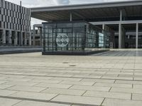 a building made out of glass and a courtyard outside with a brick walkway and a stone tile patio