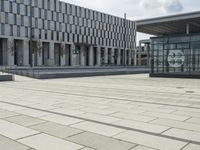 a building made out of glass and a courtyard outside with a brick walkway and a stone tile patio