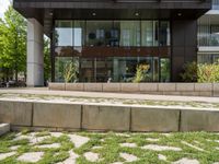 a sidewalk outside of a tall building with a glass front entrance and a bike path