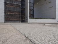 a piece of metal on the ground in front of a building with windows and concrete pillars