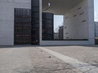 a piece of metal on the ground in front of a building with windows and concrete pillars