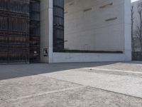 a piece of metal on the ground in front of a building with windows and concrete pillars