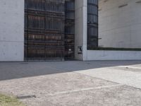 a piece of metal on the ground in front of a building with windows and concrete pillars