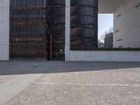 a piece of metal on the ground in front of a building with windows and concrete pillars