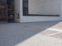 a piece of metal on the ground in front of a building with windows and concrete pillars