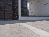 a piece of metal on the ground in front of a building with windows and concrete pillars