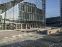 a bus stop sits in front of a building with mirrored glass windows on the side