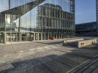 a bus stop sits in front of a building with mirrored glass windows on the side