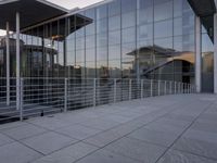 a glass and aluminum building with a staircase near a building entrance and a reflection in the glass