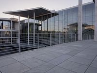 a glass and aluminum building with a staircase near a building entrance and a reflection in the glass