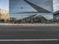 a glass facade of a building across from another structure and bus stop in front of it