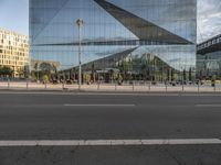 a glass facade of a building across from another structure and bus stop in front of it