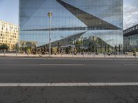 a glass facade of a building across from another structure and bus stop in front of it