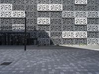 a person standing outside an artistic building covered in geometric shapes and objects in the city