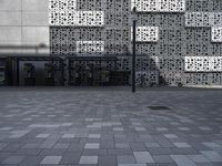 a person standing outside an artistic building covered in geometric shapes and objects in the city