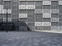 a person standing outside an artistic building covered in geometric shapes and objects in the city