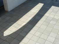 the shadow of a skateboarder in a bathroom on the tiled floor outside a bathtub