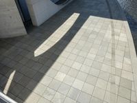 the shadow of a skateboarder in a bathroom on the tiled floor outside a bathtub