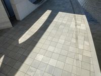 the shadow of a skateboarder in a bathroom on the tiled floor outside a bathtub