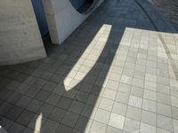 the shadow of a skateboarder in a bathroom on the tiled floor outside a bathtub