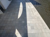 the shadow of a skateboarder in a bathroom on the tiled floor outside a bathtub