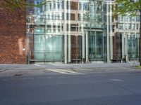 a building with glass on the top and a man riding a bike near it near a street