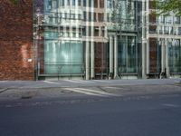 a building with glass on the top and a man riding a bike near it near a street