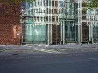 a building with glass on the top and a man riding a bike near it near a street