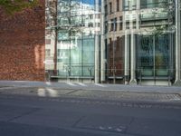 a building with glass on the top and a man riding a bike near it near a street