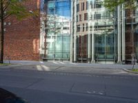 a building with glass on the top and a man riding a bike near it near a street