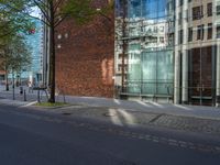 a building with glass on the top and a man riding a bike near it near a street