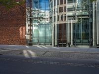 a building with glass on the top and a man riding a bike near it near a street