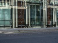 a building with glass on the top and a man riding a bike near it near a street