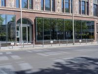 a black car is stopped in front of an empty store front building near some trees