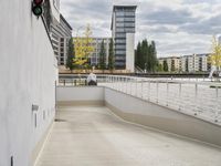 a long cement wall with no glass on it in front of a body of water and buildings