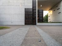 a door and two tall metal storage containers on a road near an outdoor plaza on a bright day