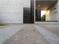 a door and two tall metal storage containers on a road near an outdoor plaza on a bright day