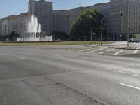 the building is very large and tall by the water fountain in the middle of the street