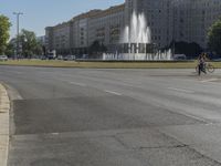 the building is very large and tall by the water fountain in the middle of the street