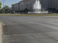 the building is very large and tall by the water fountain in the middle of the street