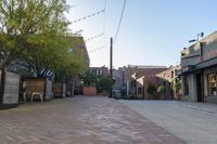 a very small brick lined street in a big town center area with buildings along both sides