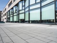 a building with glass windows on top of it and sidewalk in front of it and people walking beside it