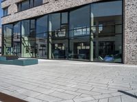 a stone walkway lined with concrete and glass windows and a small street sign on it