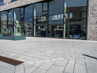 a stone walkway lined with concrete and glass windows and a small street sign on it