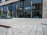 a stone walkway lined with concrete and glass windows and a small street sign on it