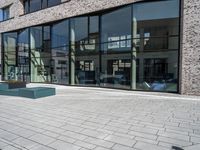 a stone walkway lined with concrete and glass windows and a small street sign on it