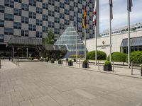 there is an entrance to a large building with flags in front of it on a walkway